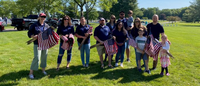 Staff and their families placing flags at the State Veterans Cemetery in Middletown, CT for Memorial Day, 2023
